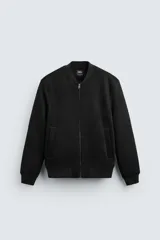 Cazadora bomber negra de corte regular, confeccionada en tejido con efecto ante. Cuenta con cuello, puños y bajo de rib elástico, bolsillos de vivo en la cadera y cierre frontal con cremallera.