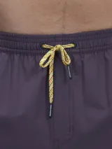 Short de baño verde con estampado de margaritas blancas y cordón ajustable naranja.