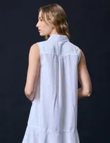 Vestido corto blanco de gasa, sin mangas, con cuello camisero, abertura central con botones y terminación de ruedo con volado.