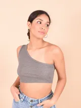 Blusa blanca de un solo hombro, corte crop top y tejido acanalado.