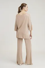 Conjunto de sweater y pantalón color beige con brillo metalizado. El sweater es holgado, de mangas 3/4 y cuello redondo. El pantalón es de corte palazzo.