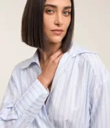Blusa celeste a rayas verticales, de tricolina, con escote en pico cruzado, lazo lateral, mangas largas y cuello solapa.