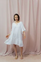 Vestido corto blanco de lino, con corte holgado, mangas cortas amplias y escote redondo con abertura en forma de V y lazo.