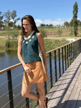 Top color beige de cuero con flecos en los laterales y caracoles buzios en el frente. Espalda tejida.