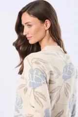 Buzo tejido en jacquard color crema con estampado de rosas azules y hojas marrones. Tiene cuello redondo y puños de rib.