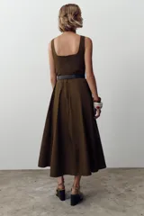 Vestido marrón midi de escote cuadrado y tirantes anchos, con cinturón negro y falda evasé. Cierre trasero con cremallera oculta.