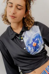Camisa crop negra con estampado de una flor y un insecto, con cintas para atar en la cintura.