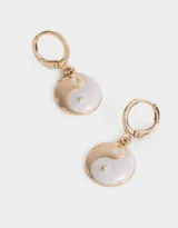 Aros dorados con forma de argolla y dije colgante con diseño de yin yang esmaltado en blanco y dorado.