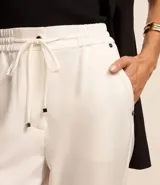 Pantalón de crepé blanco con lazo delantero en la cintura y elástico. Corte recto con botamanga arremangada.