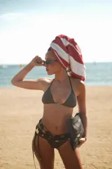 Top de bikini triangular con estampado de espirales en tonos verde y marrón, con detalle de sol plateado en el centro.