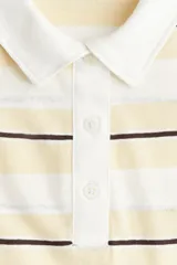 Remera polo de manga larga con rayas horizontales en tonos blanco, amarillo y negro. Tiene cuello clásico y tapeta con botones.