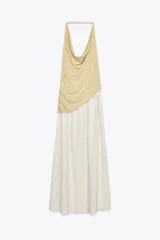 Vestido largo de fiesta con cuello halter fluido y hombros descubiertos. Presenta un top dorado drapeado y una falda larga color crema con textura.