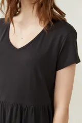 Vestido negro corto con cuello en V, manga corta y falda con volados.