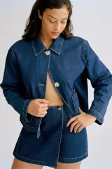 Short pollera cruzado de tiro alto en sarga de algodón color azul denim con botón a un lado, cierre oculto adelante y bolsillos insertados decorativos atrás.