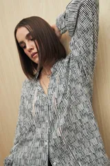 Camisa marrón con estampado animal print negro, de calce relajado, cuello clásico, abotonadura frontal y mangas largas con puños camiseros.