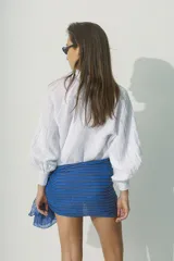 Blusa blanca de lino con cuello fruncido y botones frontales.