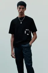 Remera negra de corte holgado con estampado blanco en el frente que incluye las letras "NY" y el número "25".