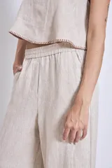 Conjunto de lino color beige, compuesto por un top sin mangas con cuello halter y un pantalón palazzo de tiro alto con cintura elastizada.
