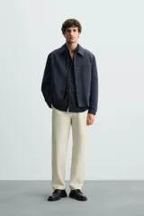 Pantalón chino color beige, corte recto, con bolsillos laterales y traseros. Cierre frontal con cremallera y botón.