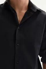 Camisa negra de manga larga con cuello italiano y tapeta lisa. Presenta un corte ajustado (slim fit) y bajo redondeado.