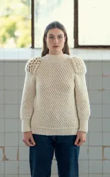 Sweater tejido a crochet color crudo, con cuello redondo, mangas largas y hombros abullonados.