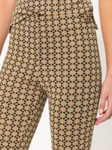 Pantalón de tiro alto con estampado geométrico en tonos beige y negro, de corte ajustado y acampanado en el ruedo.