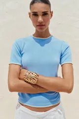 Remera blanca de punto con cuello redondo y mangas cortas con ribete negro en cuello, mangas y ruedo.