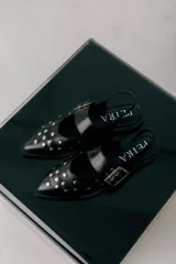 Chatas negras de cuero con punta fina y detalle de tachas plateadas.