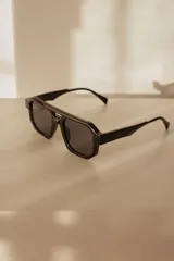 Lentes de sol de mujer con armazón grueso de policarbonato color rosa translúcido y lentes oscuros degradados. Diseño de montura geométrica con puente doble.