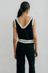 Musculosa negra con escote en V y volados blancos en el escote y las sisas.
