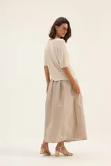 Falda larga color beige, de tafeta con moño en la cintura.