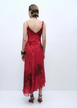 Vestido midi rojo con estampado floral, tirantes finos asimétricos, escote en pico, bajo asimétrico y abertura lateral.