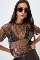 Top translúcido azul con estampado abstracto, de manga corta y tejido liviano con sutil brillo metálico.