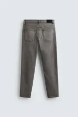 Pantalón de jean negro, corte slim fit, con tiro medio, cinco bolsillos, efecto lavado y cierre frontal con cremallera y botón.