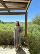 Vestido largo color beige, de corte amplio, con mangas cortas abullonadas y volado en el ruedo.