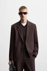 Blazer color borgoña de corte regular, con cuello de solapas de muesca, manga larga con puños abotonados, bolsillos de doble vivo en la cadera, bolsillo interior, abertura en el centro de la espalda y cierre frontal con botonadura.