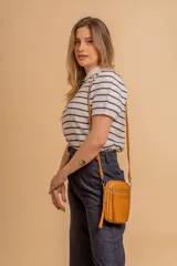 Bandolera compacta de símil cuero color rojo, con correa regulable y desmontable. Posee apertura superior, bolsillo frontal con cierre y bolsillo trasero abierto.