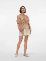 Blusa color beige con volados, cuello redondo y mangas largas abullonadas con puños abotonados.