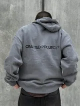Canguro gris con capucha ajustable con cordones, bolsillo tipo canguro y estampado frontal con la leyenda "CRAFTED PROJECT" y el logo de la marca.