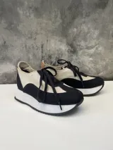 Zapatillas urbanas de cuero color blanco y negro, con cordones negros y suela de goma blanca.
