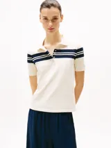 Chomba blanca de piqué de algodón elástico con rayas horizontales azul marino en cuello y mangas, corte slim, cuello de chomba con tapeta de seis botones y logo de Tommy Hilfiger bordado en la manga.