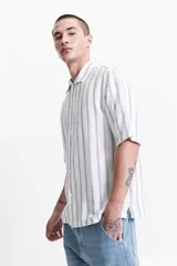 Camisa de manga corta con corte oversize, a rayas verticales blancas y grises, con cuello clásico y cierre frontal con botones. Confeccionada en algodón.