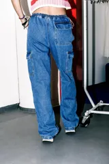 Pantalón cargo de jean celeste con lavado esfumado, tiro bajo, pierna ancha y bolsillos cargo.