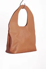 Bolso tote negro de cuero con manija circular rígida.