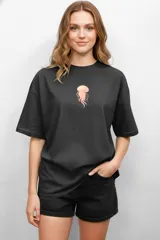 Remera negra de algodón con estampado de medusa en el pecho. Corte holgado y cuello redondo.