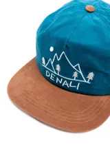 Gorra de pana azul con visera marrón y bordado frontal de montañas, árboles y la palabra "Denali".