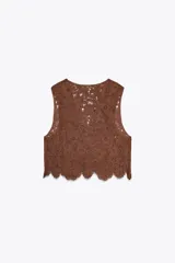 Top chaleco marrón de crochet con escote en pico y cierre frontal con lazos.