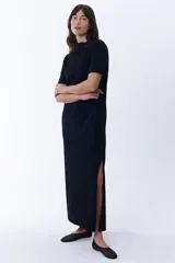 Vestido largo negro de corte recto con cuello redondo y mangas cortas. Presenta aberturas laterales en el ruedo.