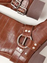 Botas cortas de cuero marrón con textura, hebillas ajustables, apliques circulares y punta cuadrada.