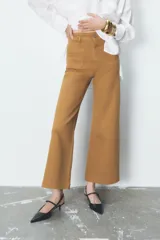 Pantalón de jean de tiro alto color negro con pierna ancha, bolsillos delanteros y traseros, y cierre frontal con cremallera y botón metálico.